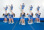 Cheerleading team performing an acrobatic stunt, with one member lifted high by the group during a routine.