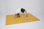 Kid doing gymnastic bridge pose on bright yellow exercise mat