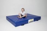 A picture of a girl sitting on the AirTumble Promat Crash Mat.