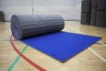 Rolled-out blue Air Tumble Track Gymnastics Mat on a gym floor, ready for tumbling or training use.