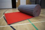 A picture of foldable red AirTumble Roll Mats on the floor of a gymnasium.