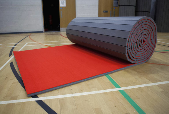 Rolled red gymnastics floor exercise mat