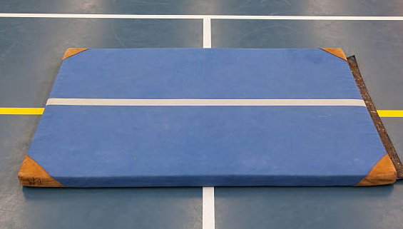 Blue Air Track gymnastics mat with white center stripe, placed on an indoor sports court with yellow and white boundary lines